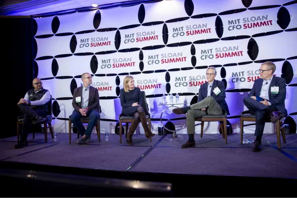 Panelists seated on stage engaging in a discussion before an audience at the MIT Sloan CFO Summit