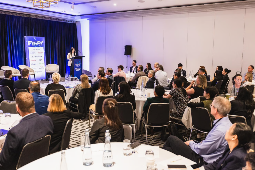 Speaker presenting at Future of Finance Summit 2025 to a full conference room audience.