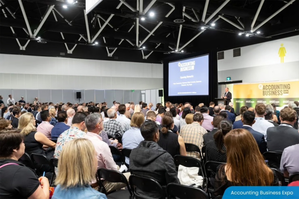 Large conference audience seated facing a speaker on stage at Accounting Business Expo.