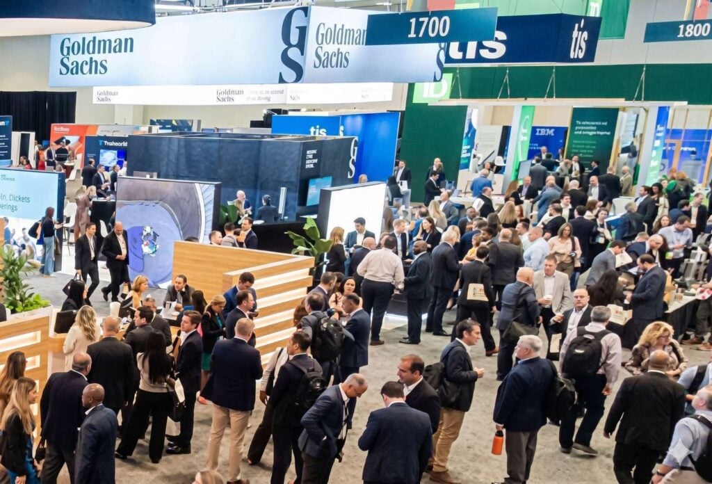 Busy conference expo hall with attendees networking among exhibitor booths from finance and technology companies